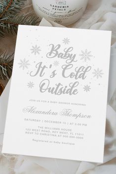 a baby it's cold outside card next to a candle and christmas tree branch