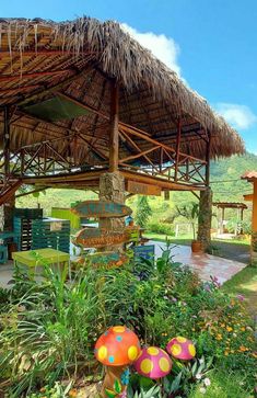 colorful mushrooms are growing in the grass under a thatched roof over an outdoor dining area