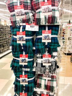 the plaid scarfs are stacked up on top of each other in a store aisle