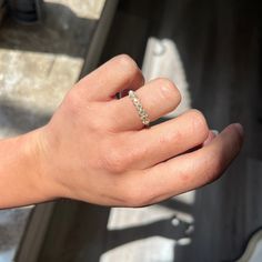 a person's hand with a diamond ring on top of their finger, outside