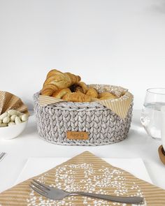 a basket filled with croissants sitting on top of a table next to a fork