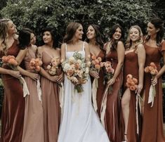 a group of women standing next to each other wearing dresses and holding bouquets in their hands