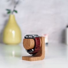 a wooden watch stand with an apple vase in the background