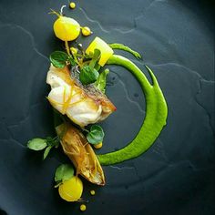 a plate topped with fish and vegetables on top of a blue table cloth covered in green sauce