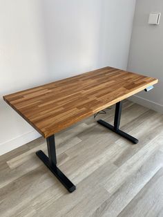 a wooden table sitting on top of a hard wood floor next to a white wall