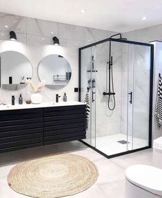 a modern bathroom with black and white fixtures, round mirrors, and marble countertops