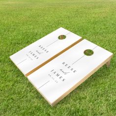 two white cornhole boards sitting in the grass