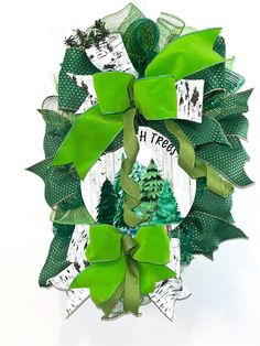 a wreath with green ribbons and trees on it