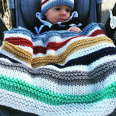 a baby is sitting in a stroller with a blanket