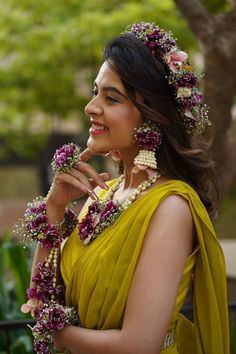 a woman in a yellow sari with flowers on her head and necklaces around her neck