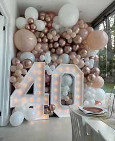 the balloon wall is decorated with white, gold and pink balloons that spell out 40