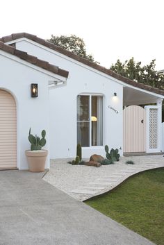 a white house with two garage doors and cactus plants