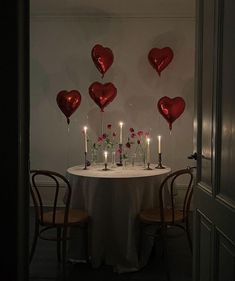 the table is set with candles and heart shaped balloons