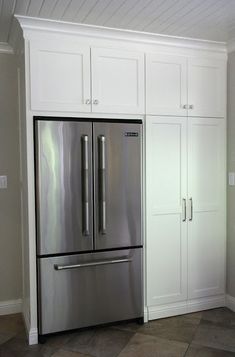 a stainless steel refrigerator in a kitchen with white cabinets