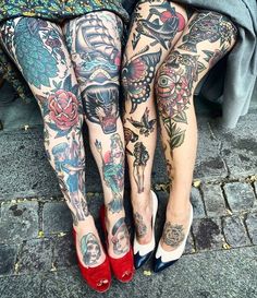 two women with tattoos on their legs sitting next to each other, both wearing high heels