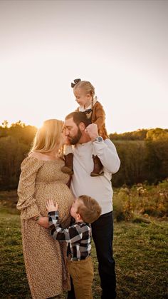 a man, woman and child are posing for a photo in the grass at sunset