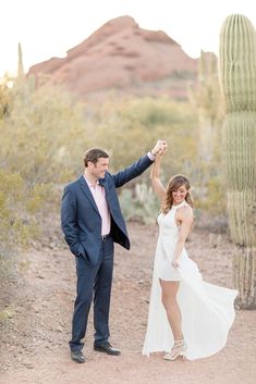 a man and woman standing next to each other in front of a saguada