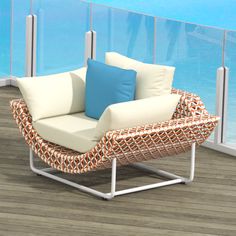 a chair with pillows on it sitting in front of a balcony overlooking the ocean and water