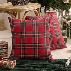 two red plaid pillows sitting on top of a bed next to a christmas tree and presents