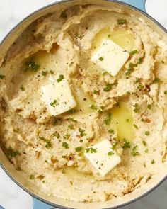 a pot filled with mashed potatoes topped with butter and chopped green onions on top