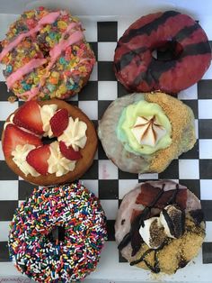 four donuts with different toppings on a checkered tray