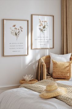 two framed pictures hang on the wall next to a bed with pillows and a straw hat