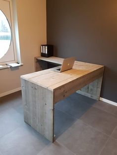 a laptop computer sitting on top of a wooden desk in front of a round window