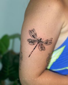 a woman's arm with a dragonfly tattoo on the left side of her arm