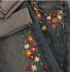 a pair of jeans with embroidered flowers on them