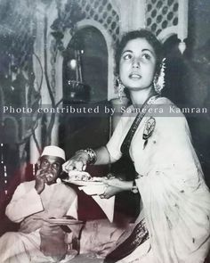 an old black and white photo of a woman serving food to a man sitting down