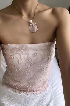 a woman wearing a pink top and white skirt with a pearl necklace on her neck