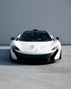 a white and black sports car parked on top of a cement floor next to a wall