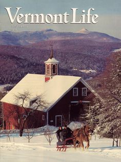 a horse drawn sleigh in front of a red barn on a snowy day