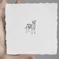 a person holding up a piece of paper with a drawing of a dog on it