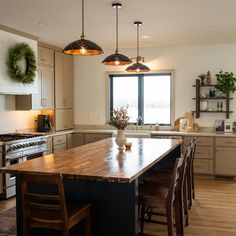 a large kitchen with an island in the middle and two lights hanging from the ceiling