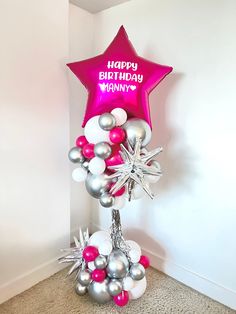 a pink star balloon with silver and white balloons on it in the corner of a room