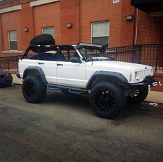 a white truck parked in front of a red brick building next to a black car