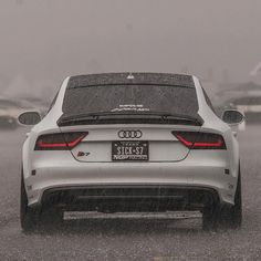 the back end of a white car driving in the rain