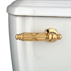 a close up of a toilet with the lid closed and gold handle on it's side