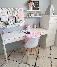 a white desk topped with a laptop computer next to a shelf filled with pink flowers