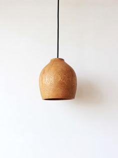 a wooden light hanging from a black cord