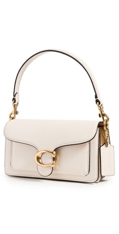 Find COACH Tabby Shoulder Bag on Editorialist. The Coach Tabby Shoulder Bag is crafted from cowhide leather and features gold-tone hardware. It has a fold-over flap with a magnetic snap closure and an optional handle and adjustable shoulder strap. The bag features a divided interior with a center zip pocket and a patch exterior pocket. It is fully lined and weighs 19 ounces. The bag measures 4.25 inches in height, 7.75 inches in length, and 2.25 inches in depth. The strap drop is 21.75 inches and the handle drop is 5 inches. Coach Tabby Bag, Coach Tabby Shoulder Bag, Coach Tabby 26, Coach Bags Outlet, Tabby Shoulder Bag, Coach Tabby, Cute Mini Backpacks, Cream Bags, Girly Bags