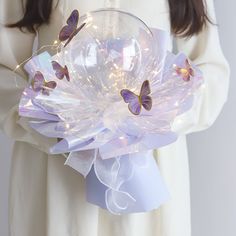 a woman holding a glass ball with butterflies on it and some lights in the background