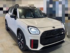 the front end of a white car in a showroom with colorful tiles on the wall