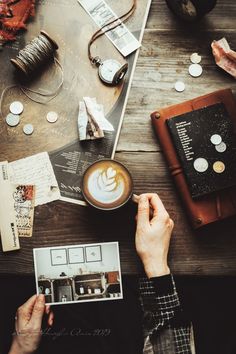 a person is sitting at a table with coffee and other things on the wooden table