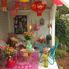 a porch covered in lots of furniture and lanterns hanging from the ceiling, with colorful decorations on it