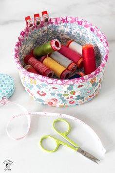 scissors, thread and spools are sitting on a table next to some sewing supplies