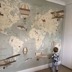 a young boy standing in front of a wall mural with airplanes and planes on it