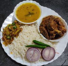 a white plate topped with rice, meat and veggies next to bowls of soup