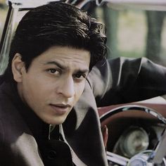 a man sitting in the driver's seat of a car looking at the camera